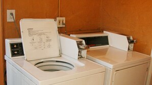 A front-loading washing machine with a control panel and a manual.