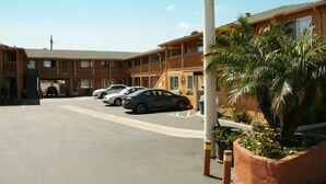 A motel with a parking lot, multiple cars, and a building with a wooden facade.