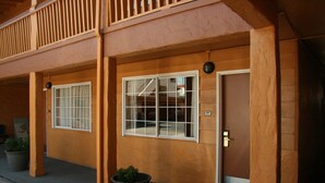 A building with a wooden facade, two large windows, and a door with a number sign.