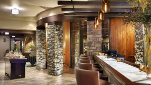 A restaurant with stone pillars, wooden beams, and a bar area with seating. - Flying Horse Resort & Club (Colorado Springs)