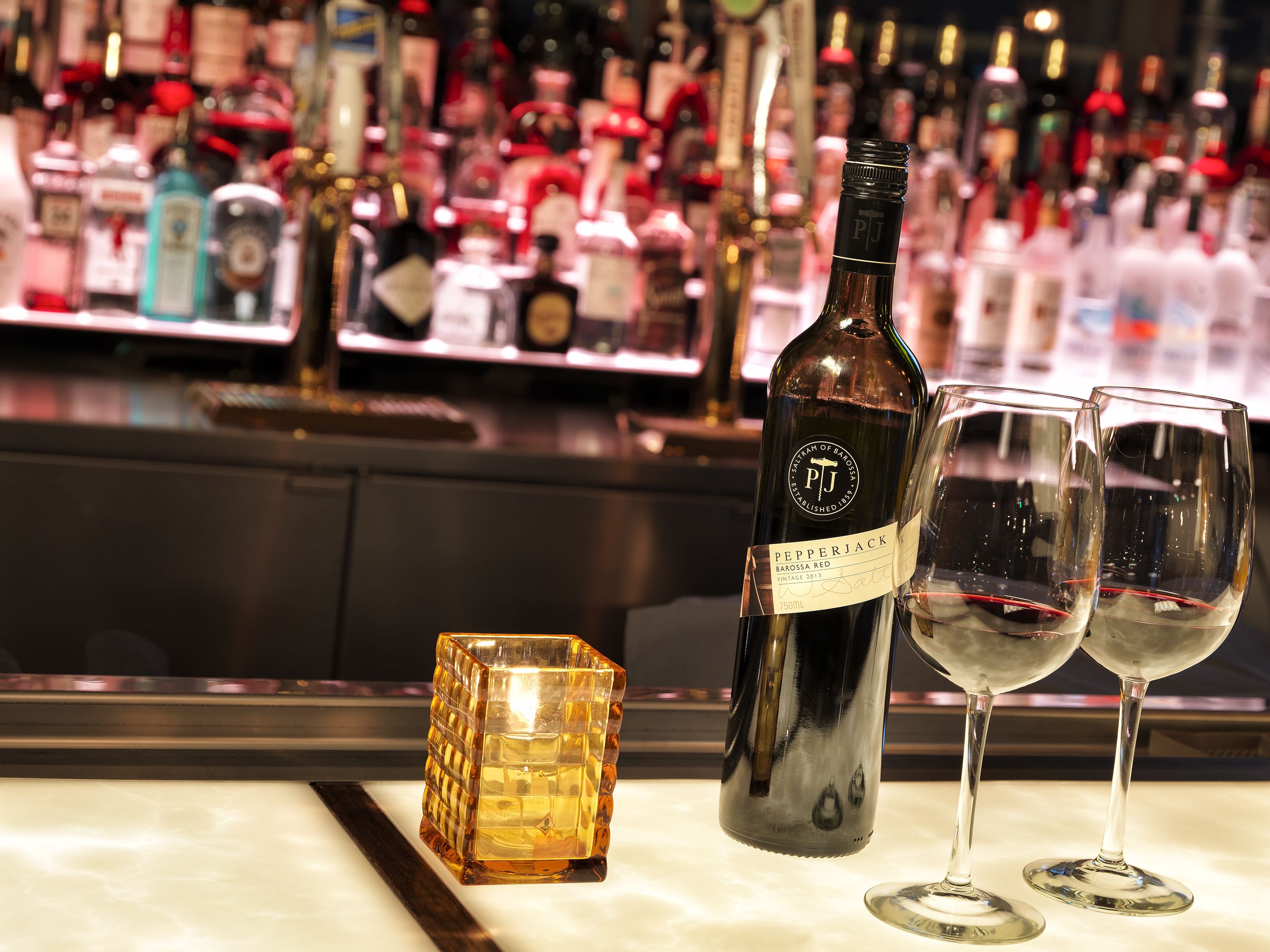 A bar setting with a bottle of wine, two glasses, and a decorative cube.
