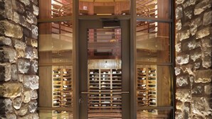 A revolving door with a glass panel, leading to a wine cellar with wooden shelves and bottles. - Flying Horse Resort & Club (Colorado Springs)