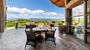 A covered patio with wicker furniture and a view of mountains. - Flying Horse Resort & Club (Colorado Springs)