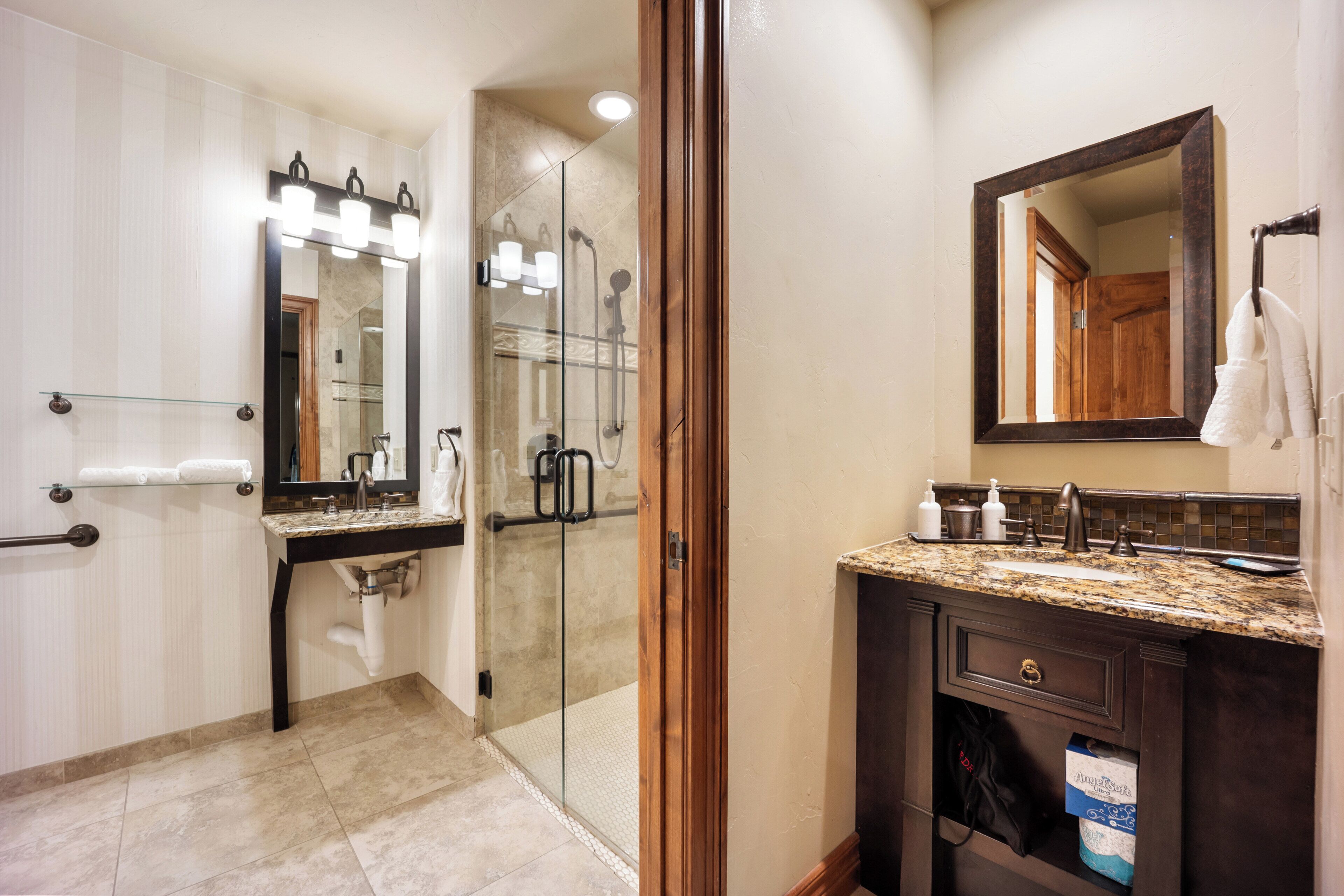 Une salle de bain moderne dotée d’une douche à parois de verre, d’un meuble-lavabo avec un plan de travail en marbre et d’un grand miroir au-dessus du lavabo.
