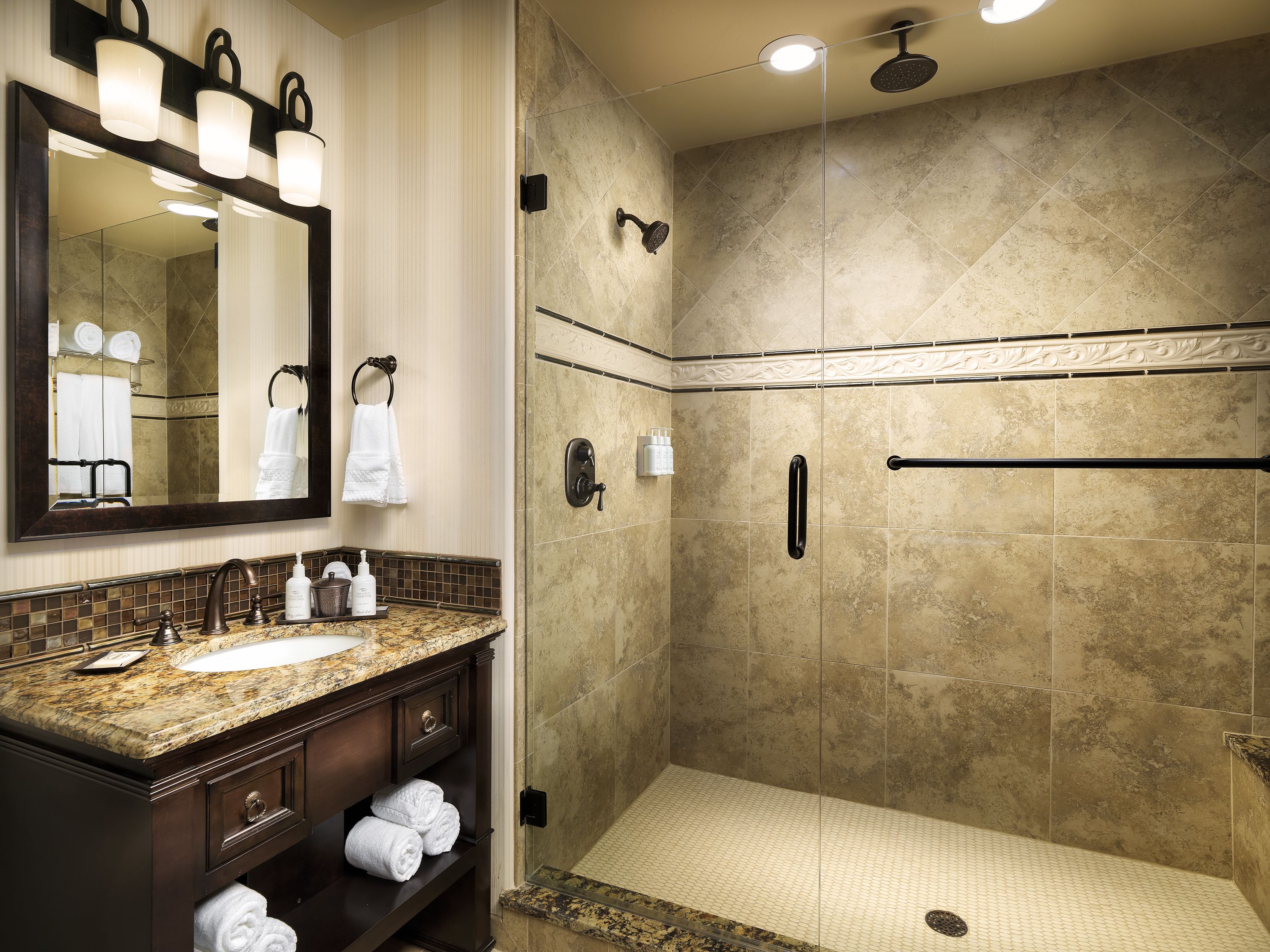 A bathroom with a sink, mirror, and shower.