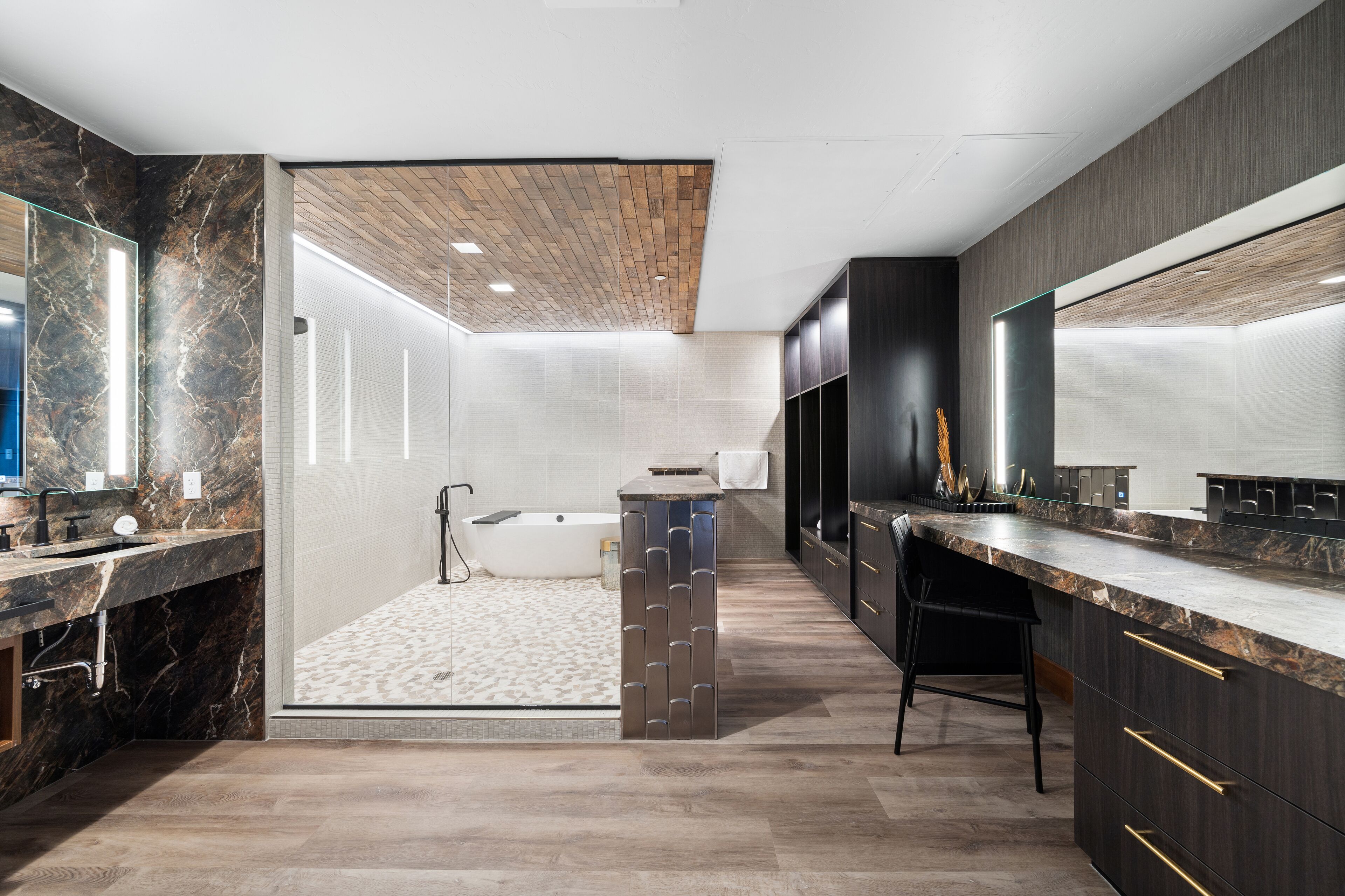 Un baño moderno con tocador de mármol, bañera independiente y un espejo grande.