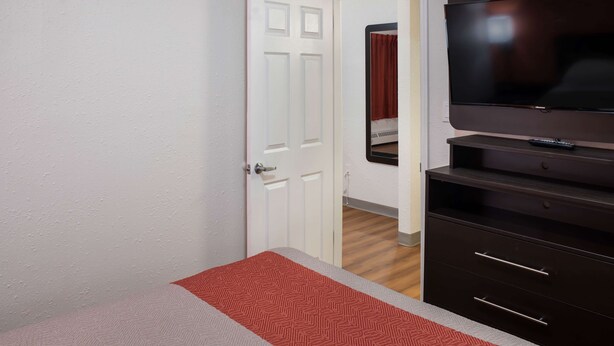 Una camera d'albergo con un letto, una televisione e un armadio.