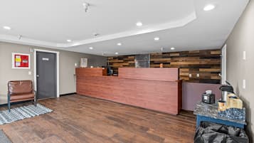 Et receptionsområde med en træreception, brandslukker, førstehjælpskasse og skraldespand.