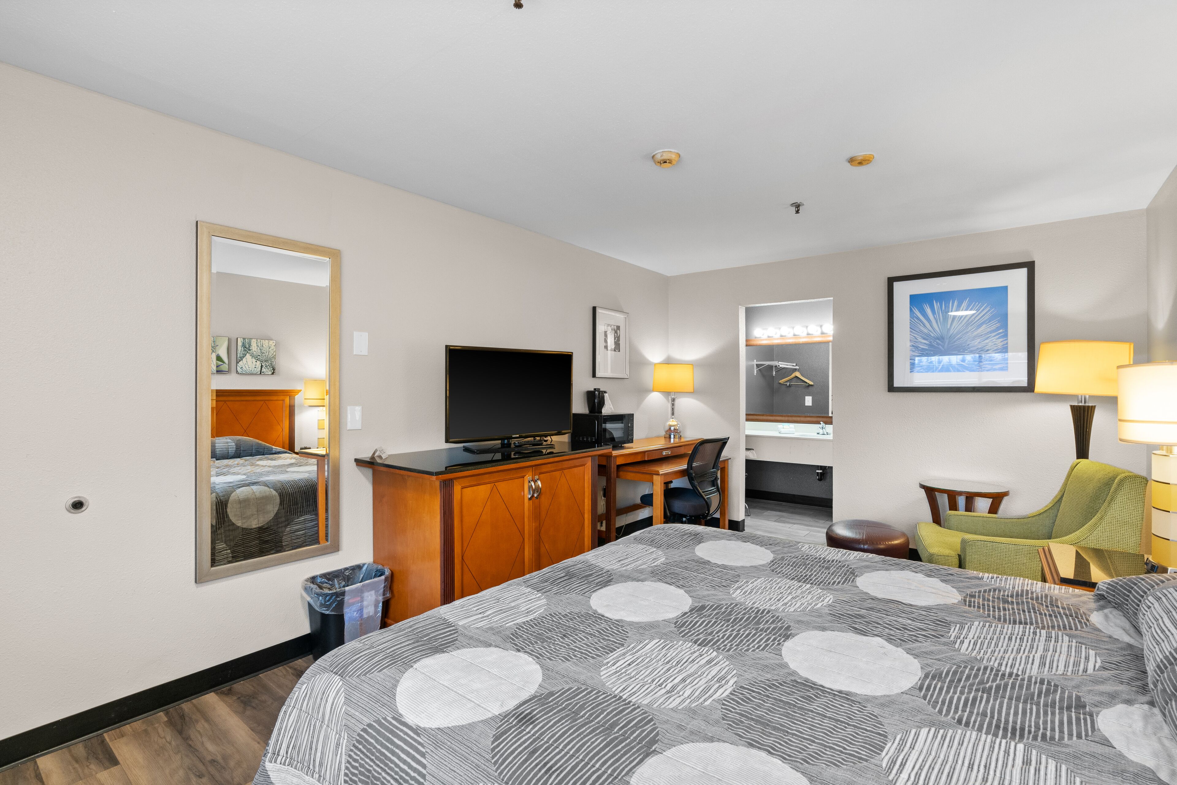 A hotel room with a large bed, a desk with a computer, a television, and a chair.