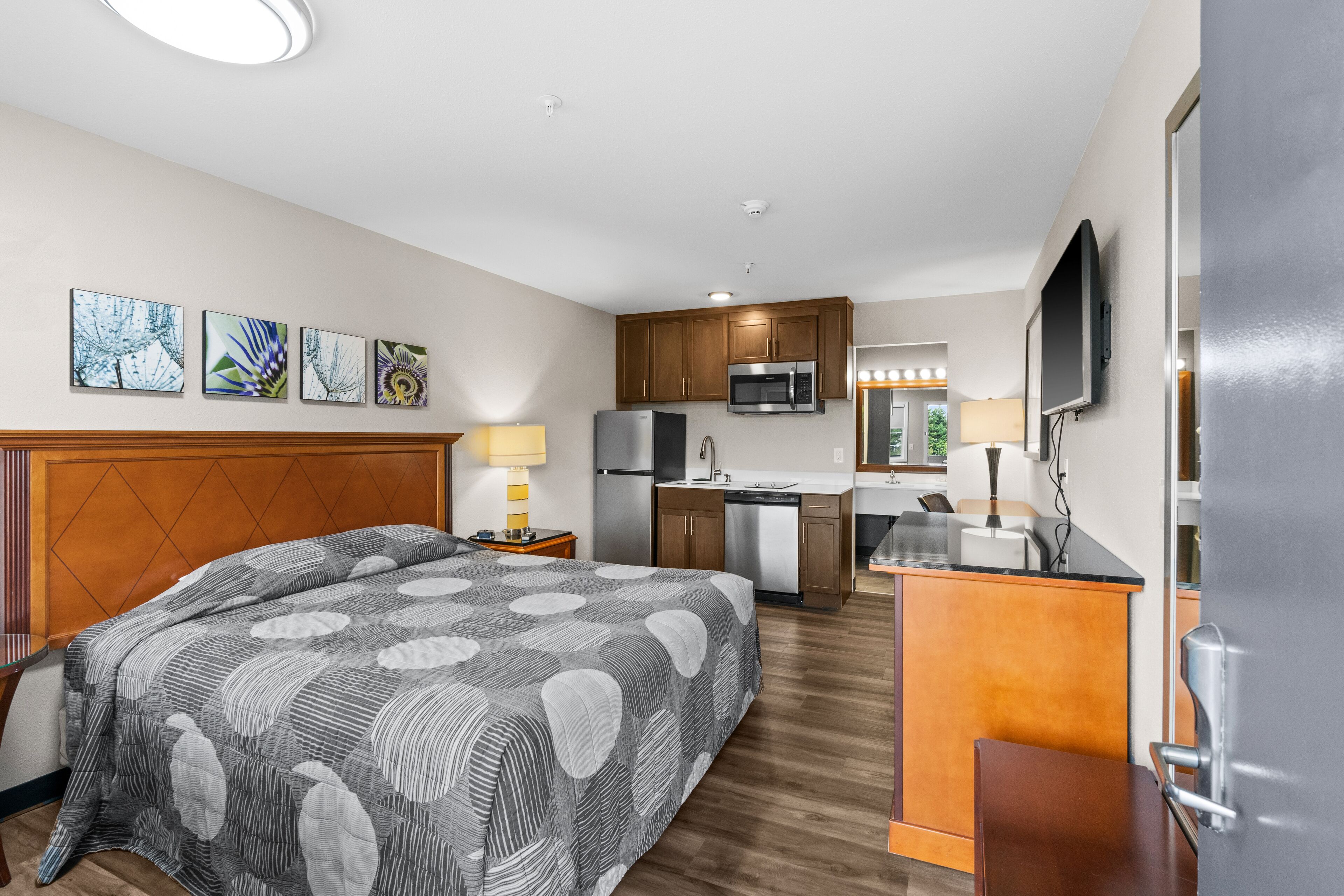 Een hotelkamer met een bed, bureau, kitchenette en televisie.