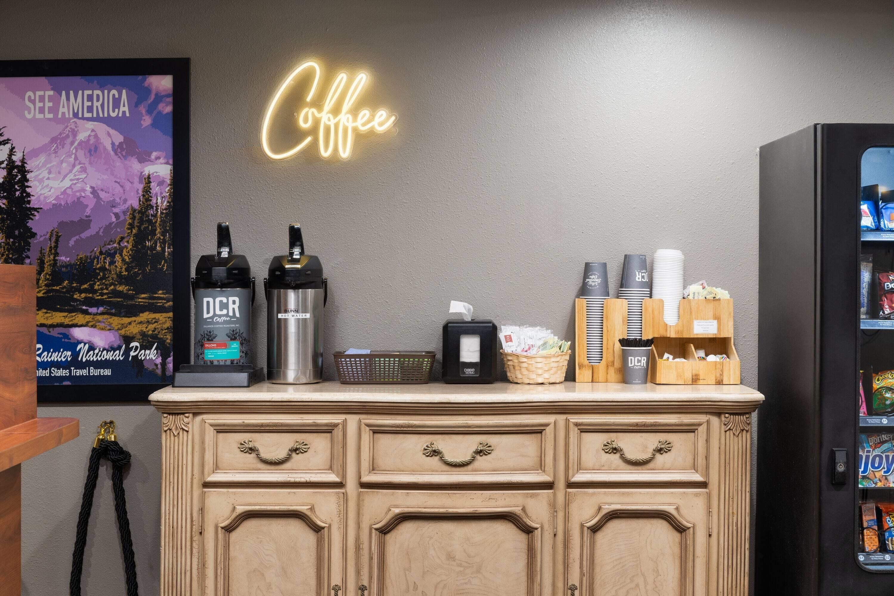 Een koffiehoek met een neonbord, DCR koffiemachines en een drankdispenser.