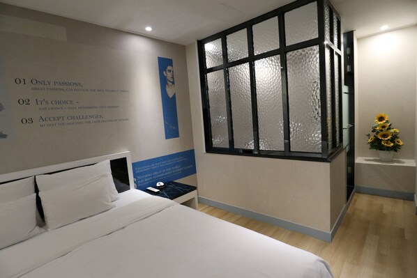A hotel room with a large bed, a small bedside table, a decorative window, and motivational posters on the wall. - Hotel Cullinan Jongno (Seoul)
