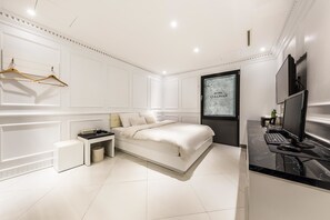 Une chambre à coucher moderne avec un lit, une table de chevet et un bureau avec un ordinateur.