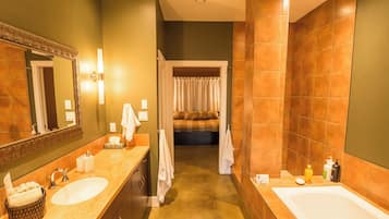 A bathroom with a large mirror, two sinks, a bathtub, and a shower area.