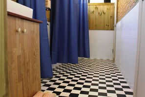 Un baño con piso de cuadros, muebles de madera y cortinas de ducha azules.