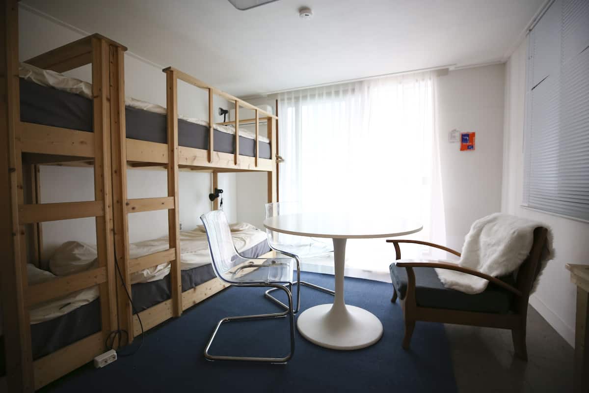 A room with bunk beds, a round table, and two chairs.
