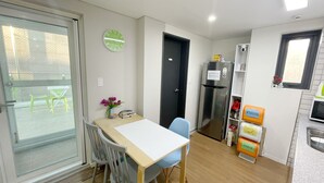 A compact kitchen with a refrigerator, a microwave, and a small dining area with a table and chairs. - Dream Comfort (Seoul)