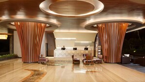 Een moderne lobby met een receptiebalie, een zithoek en een opvallend rond plafond.