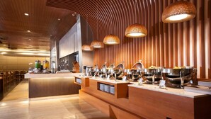 Een buffetgedeelte met meerdere aanzitpunten, houten toonbanken en hangende pendelverlichting.