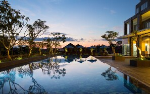 Un área de piscina tranquila con reflejos claros, rodeada de árboles y edificios modernos.