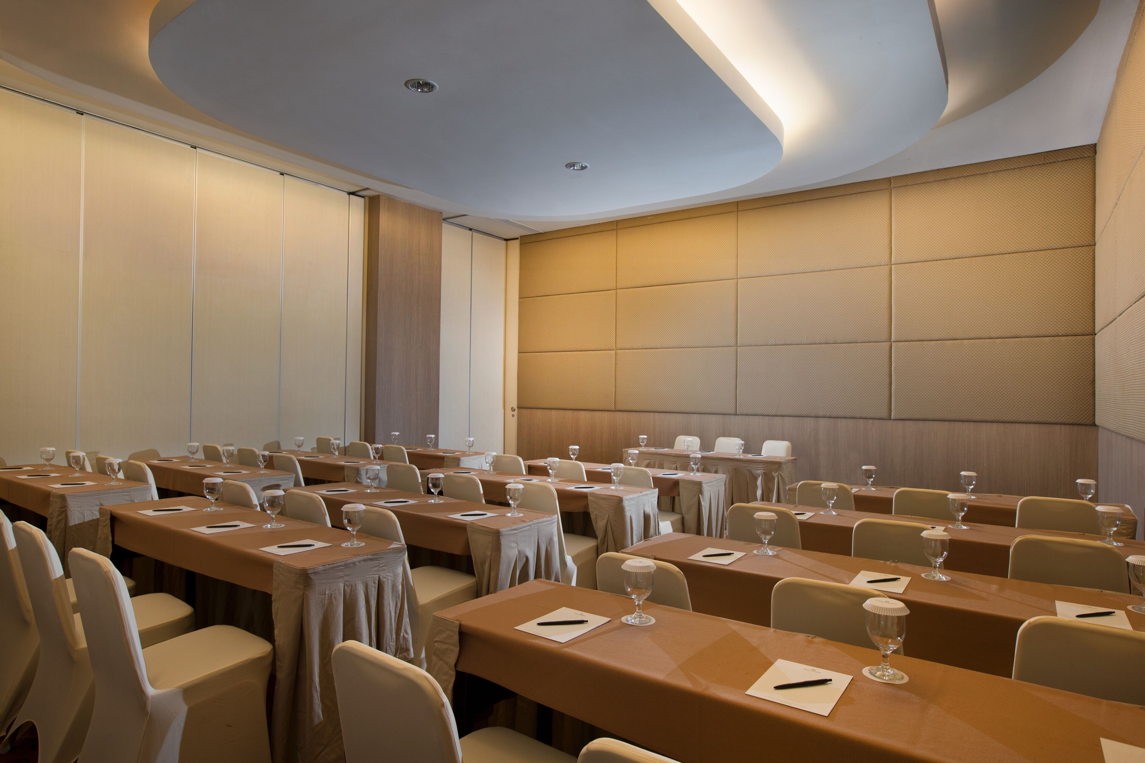 Un salón de conferencias con varias mesas y sillas, equipado con tarjetas de identificación y copas de vino.