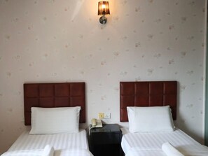 A hotel room with two beds, a nightstand with a telephone, and a wall-mounted light fixture. - Hotel O D Nice Inn Hotel (Kuala Lumpur)