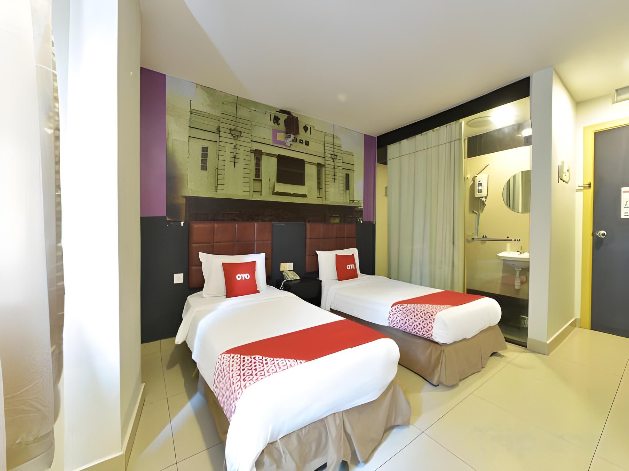 A hotel room with two beds, a bathroom, and a view of a building.