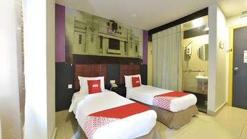 A hotel room with two beds, a bathroom, and a view of a building.