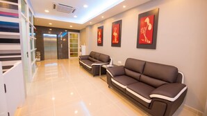 A modern hotel lobby with two sofas, a small table, and a staircase. - G langkawi Motel (Langkawi)