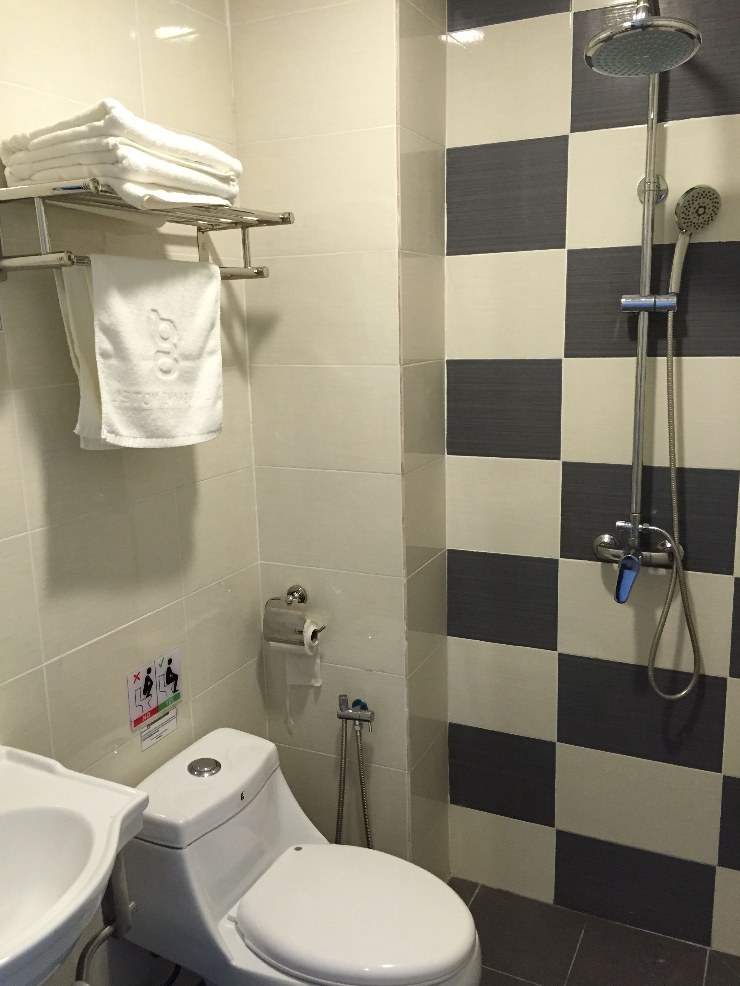 Bagno con toilette, lavandino e doccia con parete a scacchi.