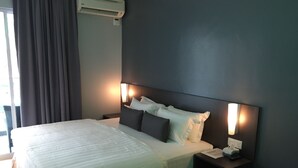 A hotel room with a large bed, a bedside table with a lamp, and a wall-mounted air conditioner. - G langkawi Motel (Langkawi)