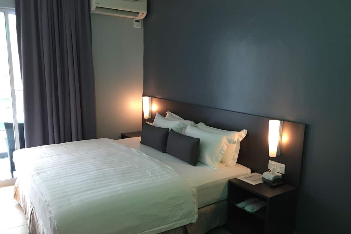 Une chambre d’hôtel avec un grand lit, une table de chevet avec une lampe et un climatiseur fixé au mur.