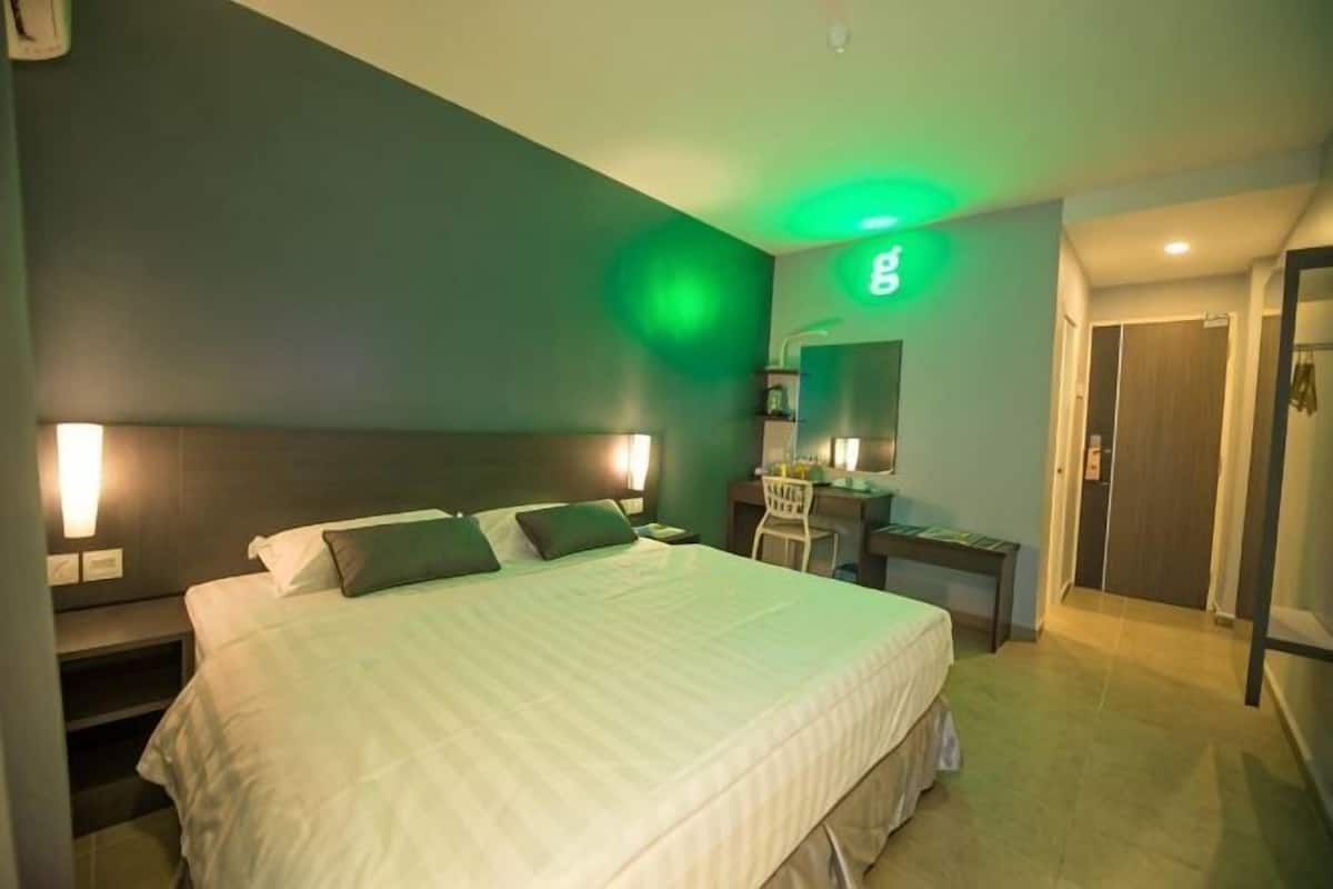 Une chambre d’hôtel comprenant un lit, des tables de chevet, un bureau, une chaise, un miroir et une porte.