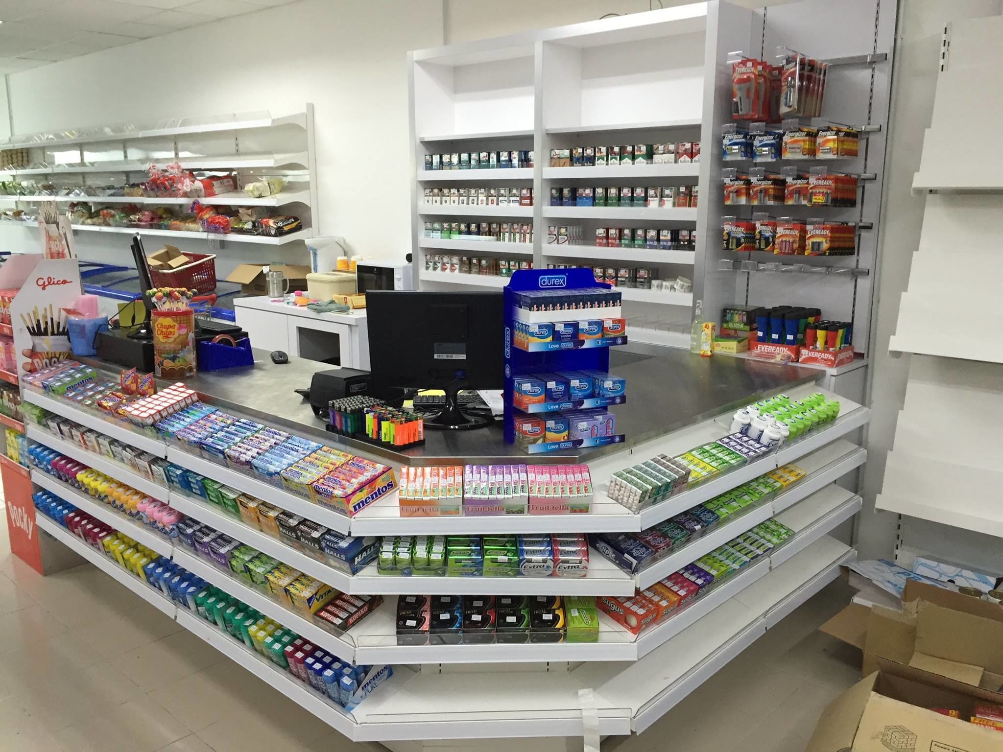 A pharmacy with shelves stocked with various health and beauty products, a computer, and a cash register.