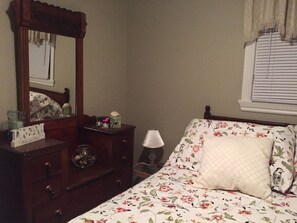 A bedroom with a bed, a dresser, a mirror, a lamp, and a window with blinds. - Greenwich Moonlight Bay Cottage (Greenwich)