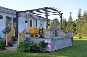A covered patio with outdoor furniture, a wooden deck, and potted plants. - Greenwich Moonlight Bay Cottage (Greenwich)