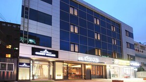 Un hotel moderno con un llamativo letrero que dice "The Nomad", varios pisos y fachada de vidrio.