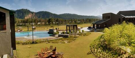 A pool area with a wooden deck, lounge chairs, and a gazebo.