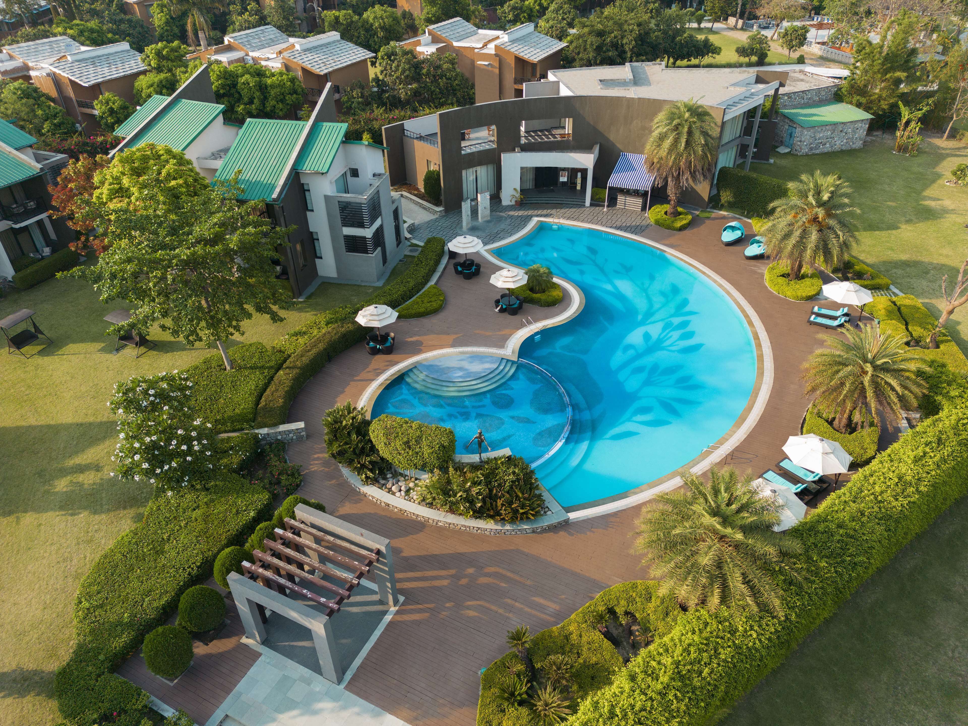 A resort with a large swimming pool, multiple guest rooms, and lush landscaping.