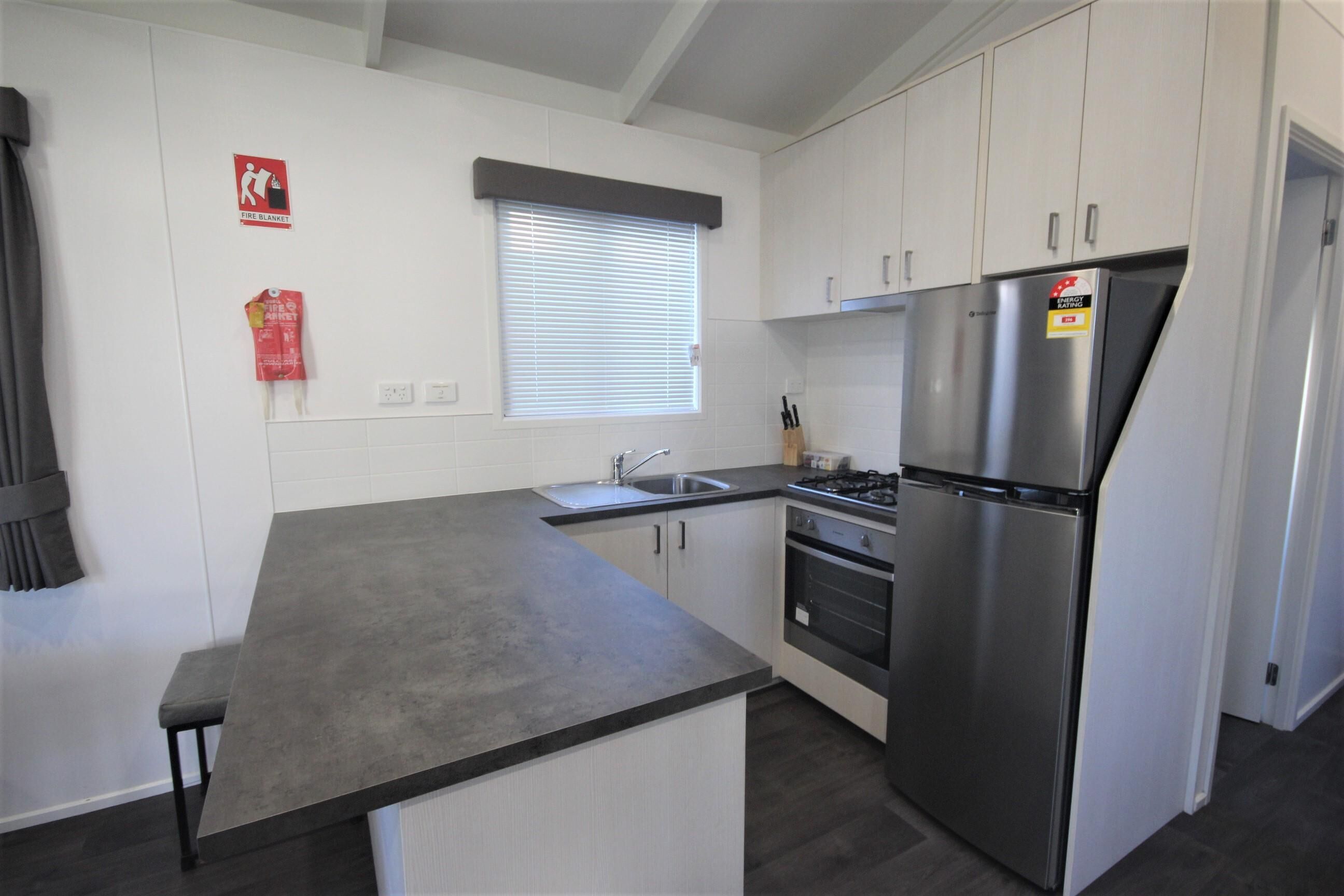 A modern kitchen with white cabinets, a stainless steel refrigerator, a gas stove, and a sink.