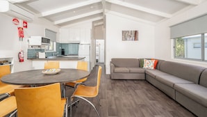 A modern kitchen with white cabinets, a microwave, and a dining area with a round table and chairs.