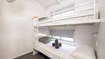 Dormitorio con literas, ventana, calefactor y ventilador.