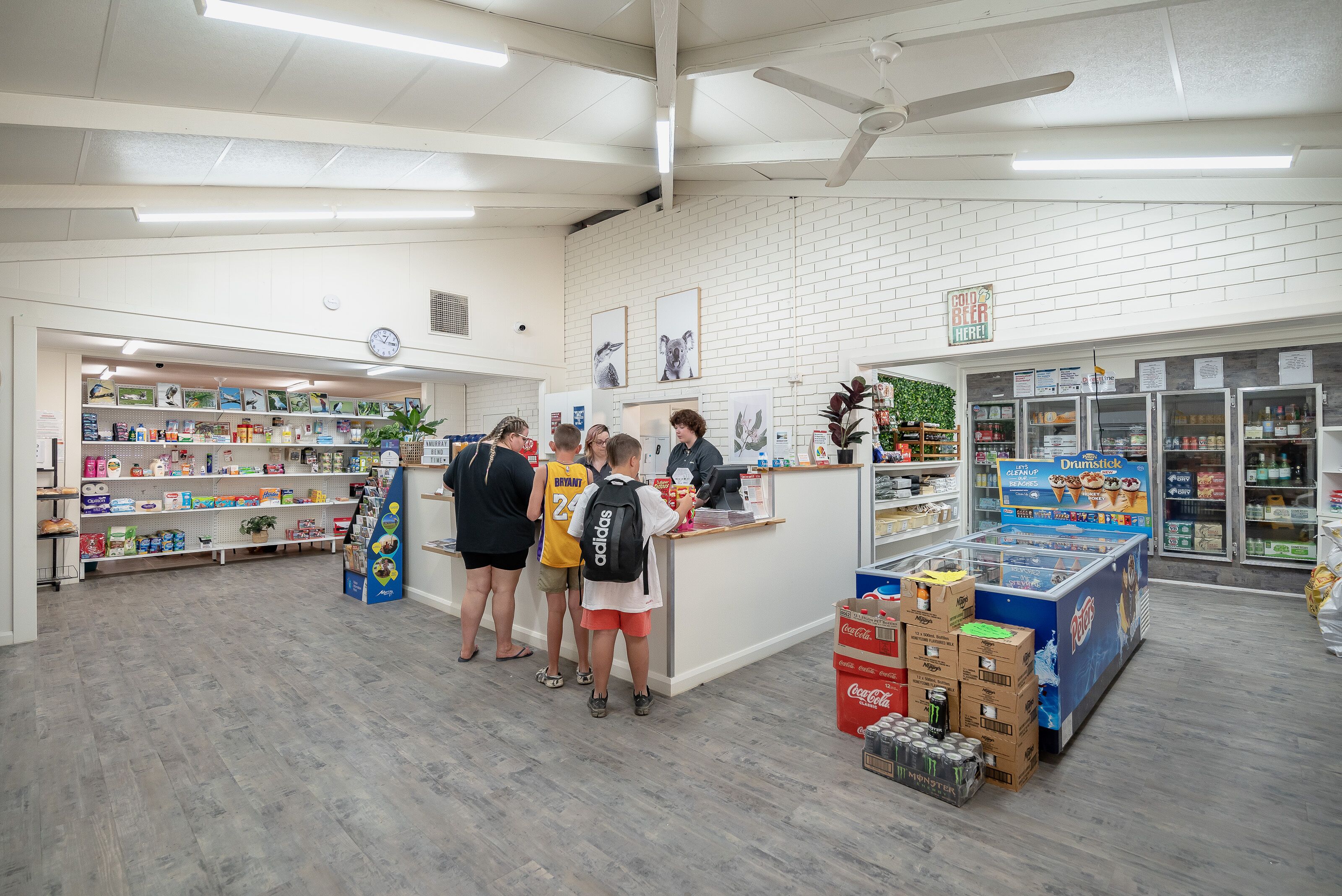 A store interior with a counter, shelves stocked with various products, and a display of beverages.