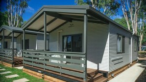 A mobile home with a covered porch and a fenced deck.