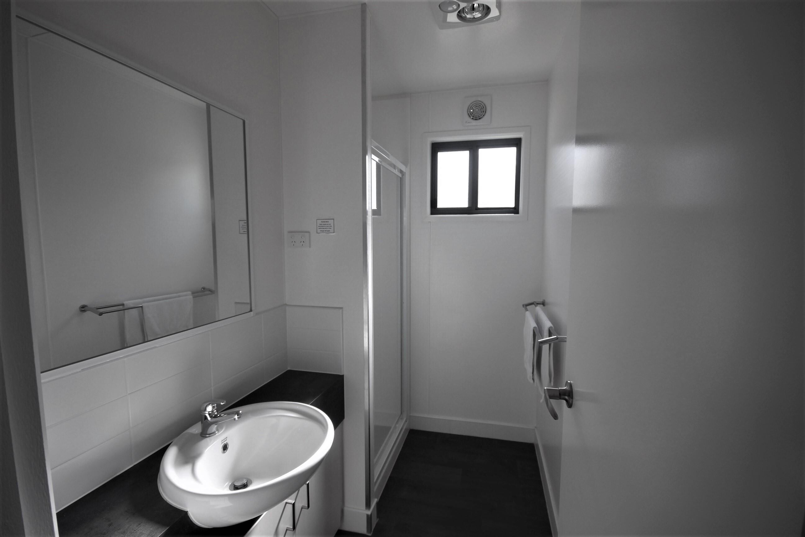 Baño pequeño y funcional con lavamanos, espejo y una ventana.