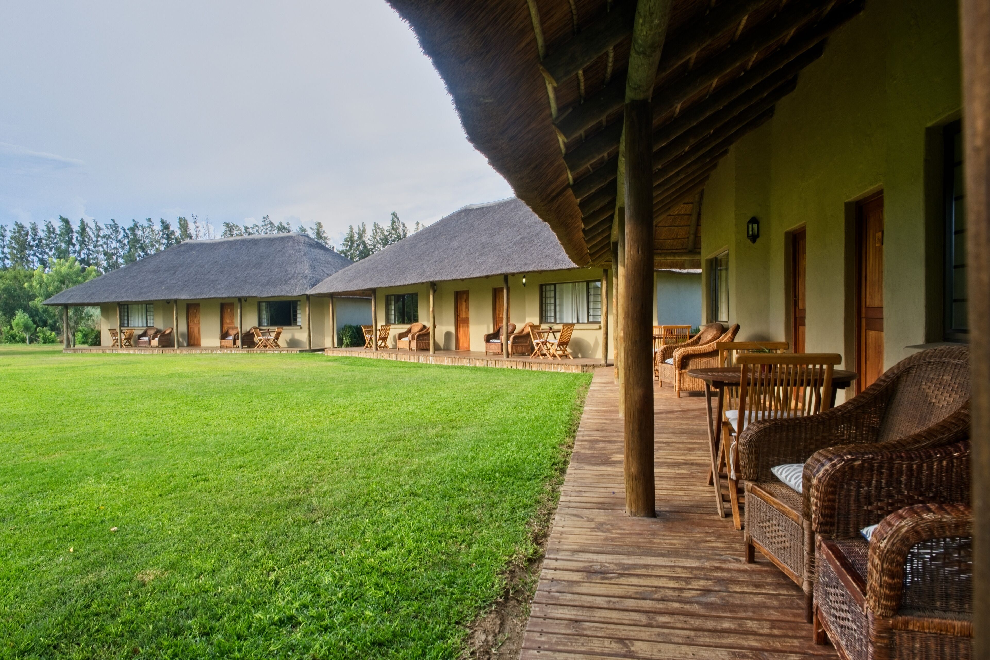 A hotel with a covered porch, outdoor seating, and a well-maintained lawn.