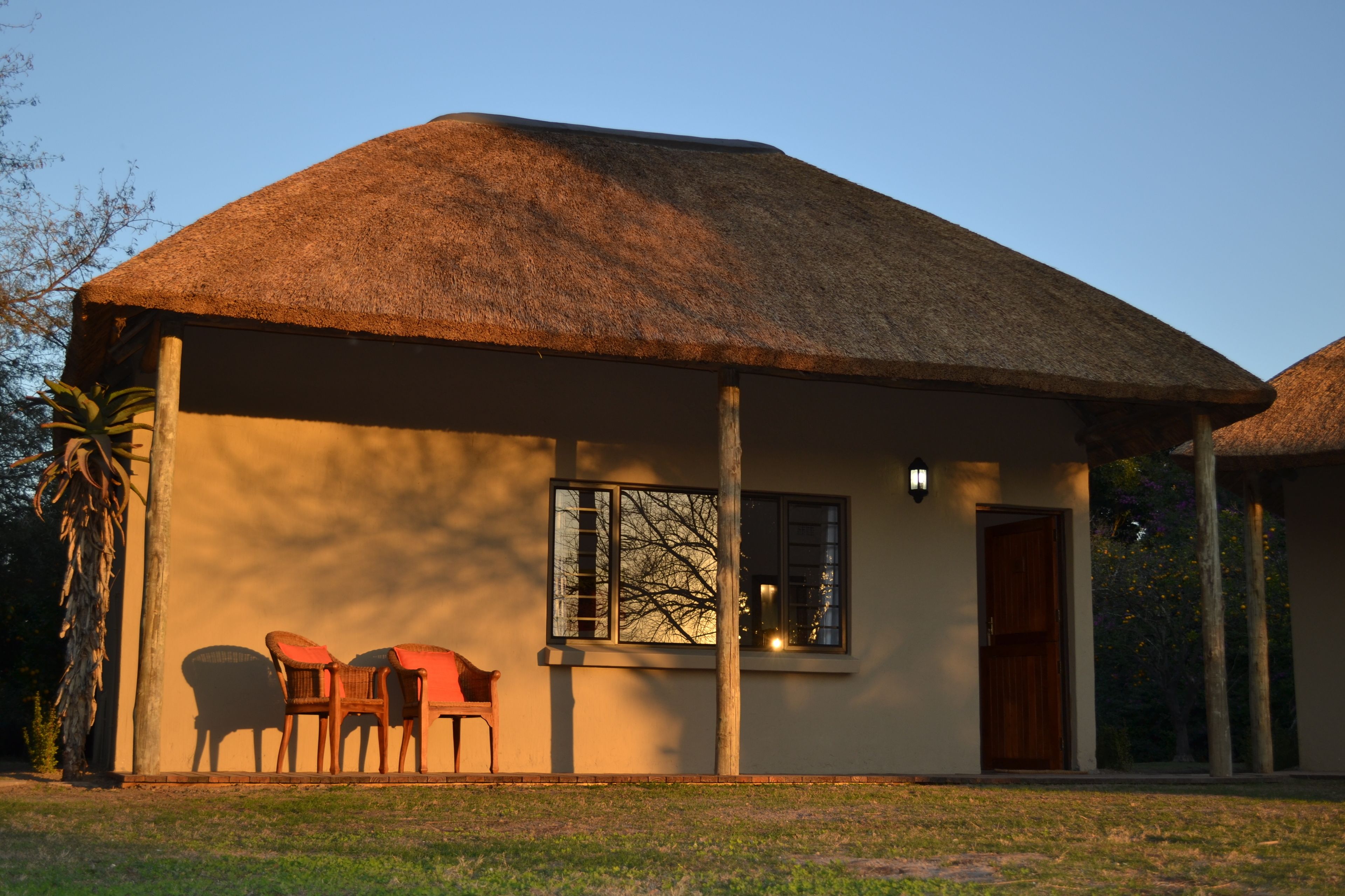 A thatched-roof building with a covered porch, a window, and a door.