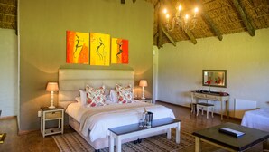 A bedroom with a bed, bedside tables, a desk, and a chair. There are three wall-mounted artworks above the bed. - Chrislin African Lodge (Addo)