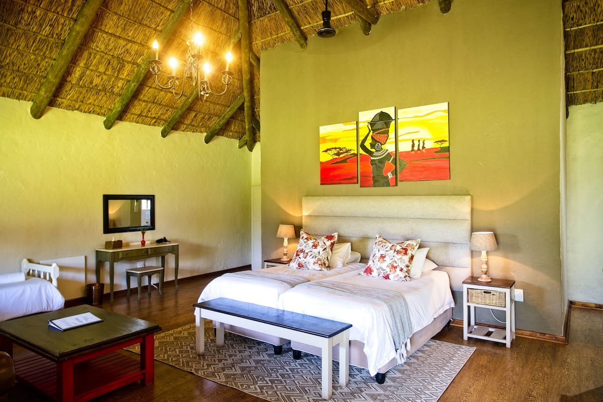 A bedroom with a bed, bedside tables, a bench, a desk, and a television.