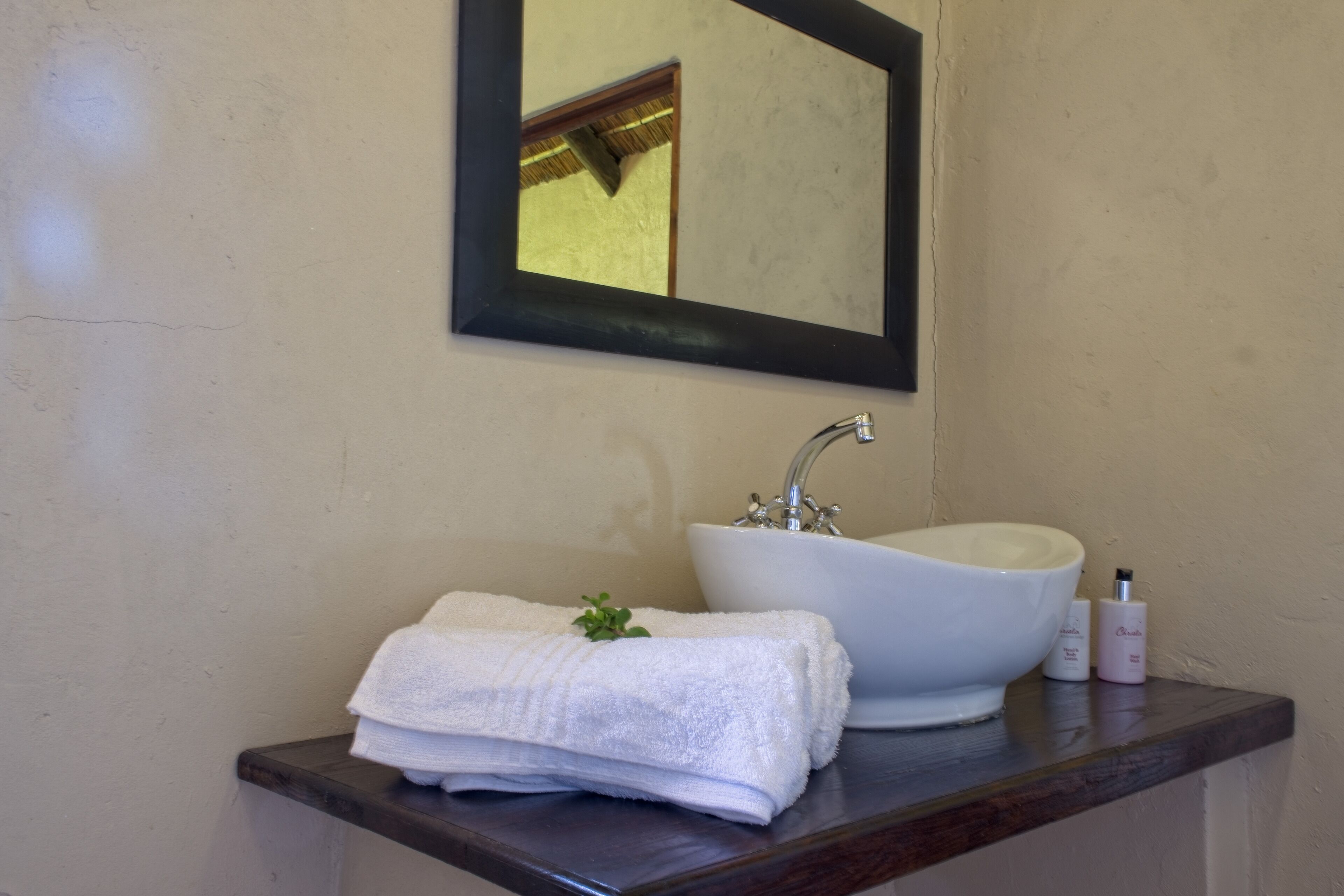Un baño con un lavamanos blanco, un espejo y una encimera de madera.